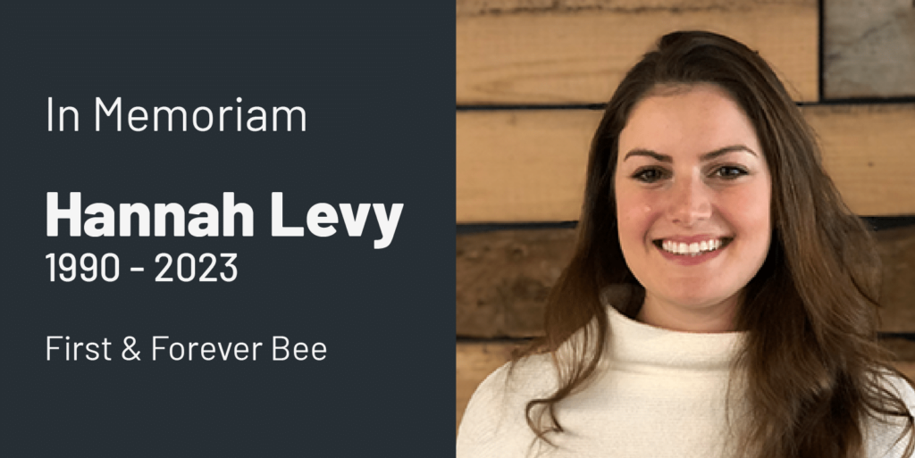 A remembrance image with the text In Memoriam Hannah Levy 1990–2023 First & Forever Bee beside a smiling woman with long brown hair in a white turtleneck, standing before a wooden wall.